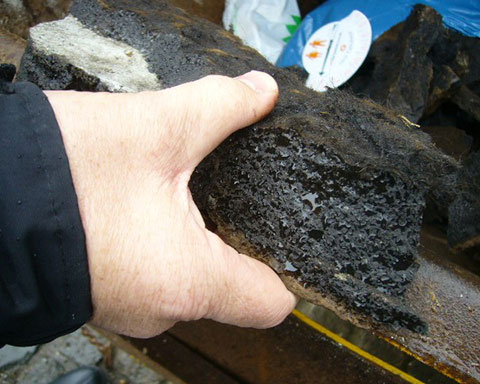 Several-inches-of-asphalt-coated-with-bitumen-removed-by-COVAC-from-a-concrete-water-tank-in-a-UK-tower-block